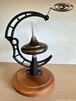 Front view showing brass rotor on black cast metal frame and wooden base