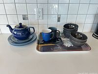 Group shot of all items including teapot, plates, bowls, mugs, square plate and rooster tray