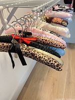 Row of padded satin hangers on rack showing variety of colors