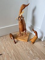 Three wooden duck figurines on bases displayed together
