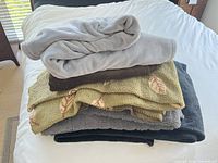 Stack of five folded throw blankets showing colors and textures