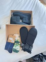Boots in box with two packaged crew socks and slipper socks displayed