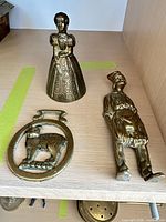 Three brass figural pieces on shelf