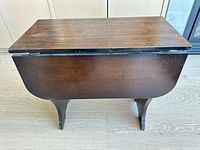 Side view of closed table showing dark brown finish and leaf seams
