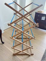 Overall view of extended wooden drying rack showing X-frame structure and blue rods