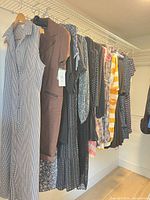 Row of nine dresses on hangers displaying variety, sizes and colours