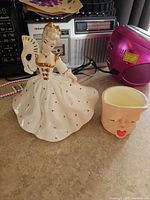 Lady figurine and face planter side by side on countertop