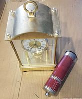 Brass glass mantel clock and red cylindrical shaker full view