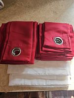 Stacked red grommet curtains over white sheer panels