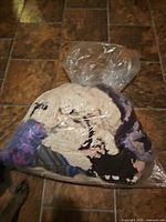 Full view of the clear garbage bag packed with assorted yarn pieces on tiled floor