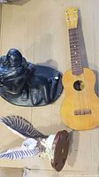 Ukulele beside two statues showing overall lot