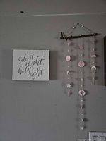 Sign and polymer clay mobile displayed on wall