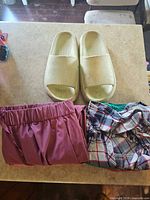 Overall lot: beige slide sandals, mauve shorts, plaid shirt, green garment visible
