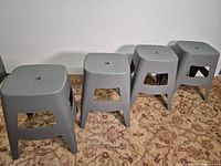 Four gray plastic Otis stools lined up