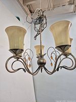 Full view of five-arm bronze-tone chandelier with glass shades
