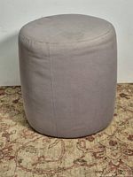 Side view of grey cylindrical ottoman