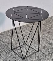 Full view of round metal side table on carpeted floor