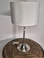 Full view of lamp on table showing shade, stem, base, cord
