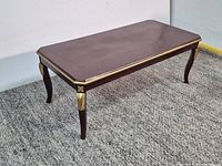 Full view of wooden coffee table showing top, legs, and gold accents