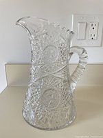 Front view of clear cut glass crystal pitcher showing star and hobstar pattern