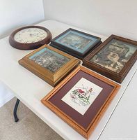 All five items on table: wall clock and four framed artworks