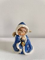 Front view of blue-cloaked angel figurine holding lantern