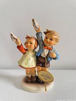 Front view of Goebel Hummel Millennium 2000 figurine showing tag and raised handkerchiefs