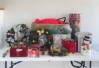 Full lot on table showing tree box, wreaths, garland, ornaments, cookie jar, Santa figure box, glass bowl box