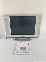 Front view of Sylvania LD200SL8 TV on stand with manual in foreground