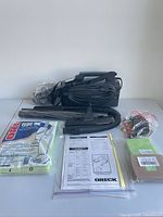 Overall lot showing vacuum, hose, attachments, bags and manuals