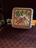front view of square ceramic asparagus plaque on chair