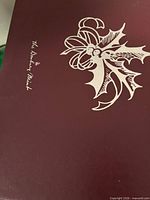 Maroon presentation box lid showing The Danbury Mint logo and holly-bow graphic
