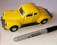 Yellow 1940 Ford Coupe diecast model car beside Sharpie for scale