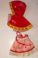 Red cape and pink skirt laid flat showing strawberry motifs and lace trim