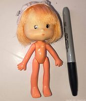 Front view of 1980 Strawberry Shortcake doll next to Sharpie for scale