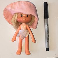 Front view of Strawberry Shortcake doll beside marker for scale