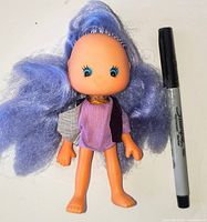 Front view of Jelly Bean doll beside marker for scale