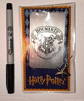 Front view of packaged 2001 Harry Potter metal Hogwarts bookmark showing crest, charm and scale reference