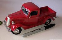 oblique view of red Ford diecast pickup truck beside marker for scale