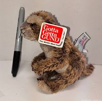 Side view of Gund Telus Meerkat plush beside Sharpie for scale, showing hang tag and fabric tag