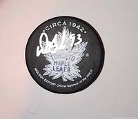Front view of signed Toronto Maple Leafs puck showing logo, Circa 1942 text and full Doug Gilmour autograph