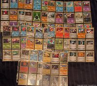 Full spread of assorted Pokémon cards laid out and binder pages visible