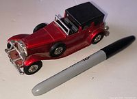Full side view of red Matchbox Town Car beside marker for scale