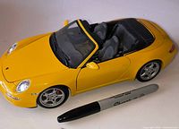 Left front side of yellow Porsche diecast with marker for scale