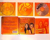 Front view showing tin lid with portrait and title, three CDs displayed