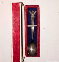 Spoon in open red box showing blue felt lining and Garuda crest