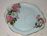 Front of saucer showing floral design, scalloped edge, gold trim