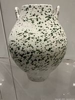 Front view of white ceramic vase with green splatter and two handles