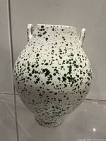 Front view of white ceramic vase with green splatter