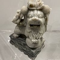 Front view of carved stone guardian lion figurine on base